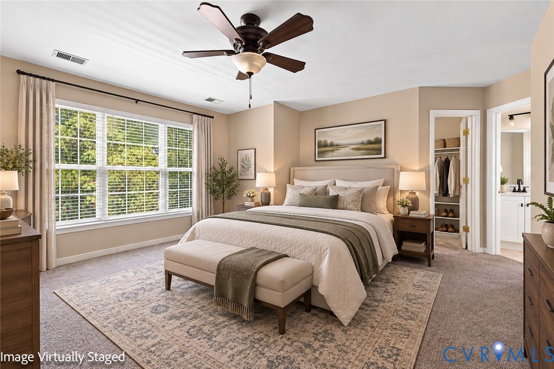 Carpeted bedroom featuring a large window with blinds, ceiling fan, and built-in closet storage