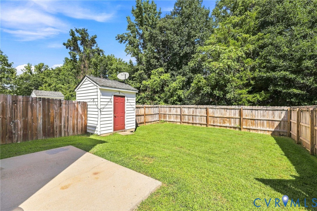Expansive backyard with a manicured lawn, wood privacy fencing, and a white storage shed with a red door Expansive backyard with a manicured lawn, wood privacy fencing, and a white storage shed with a red door