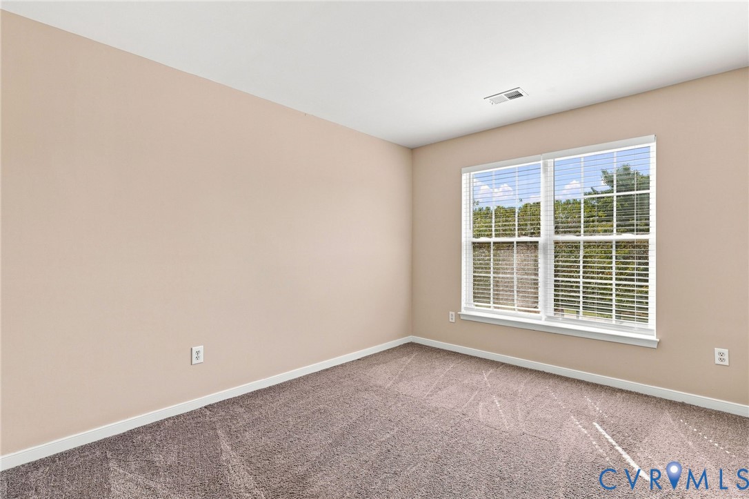 Wall-to-wall carpeting, neutral wall color, large closet and a large window with white blinds
