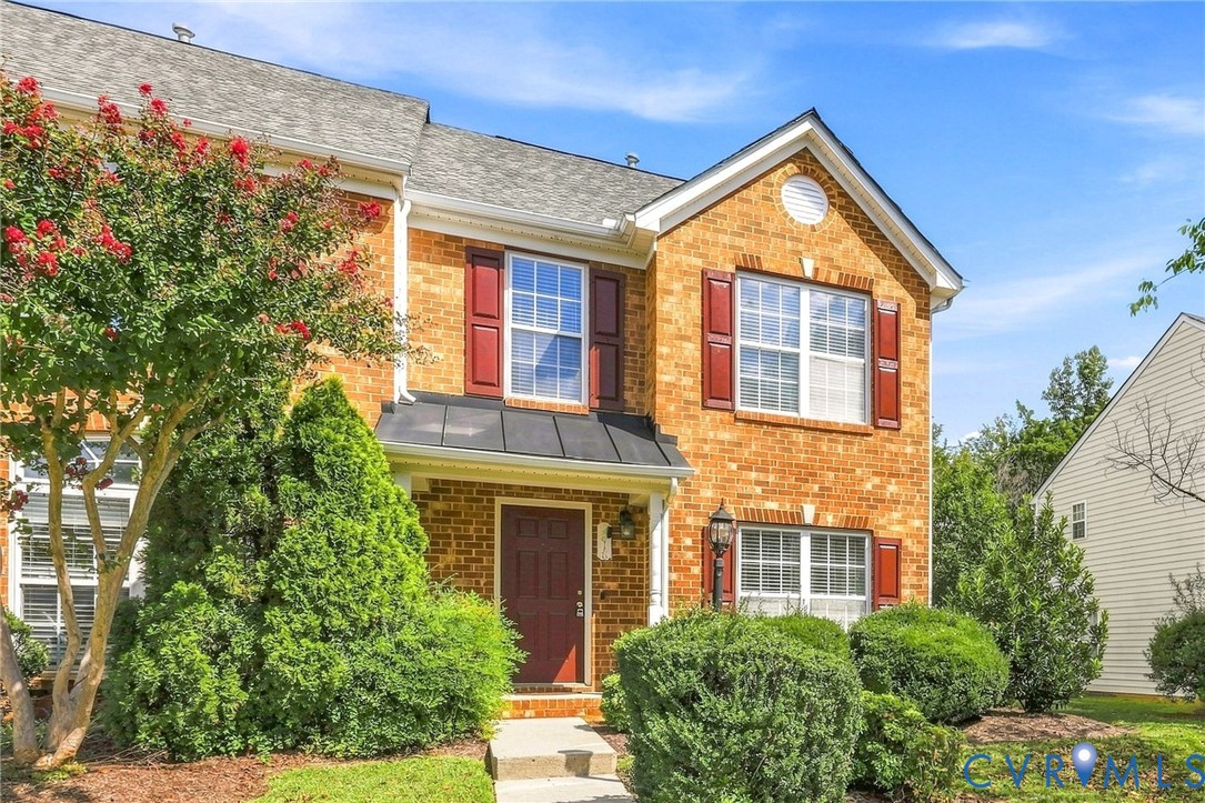 Brick exterior with red shutters, a dark entry door, and a covered porch