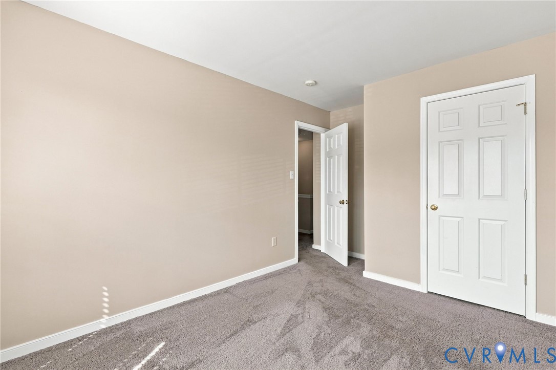 Neutral tone wall paint, gray carpet, white trim, white six-panel door, recessed lighting.