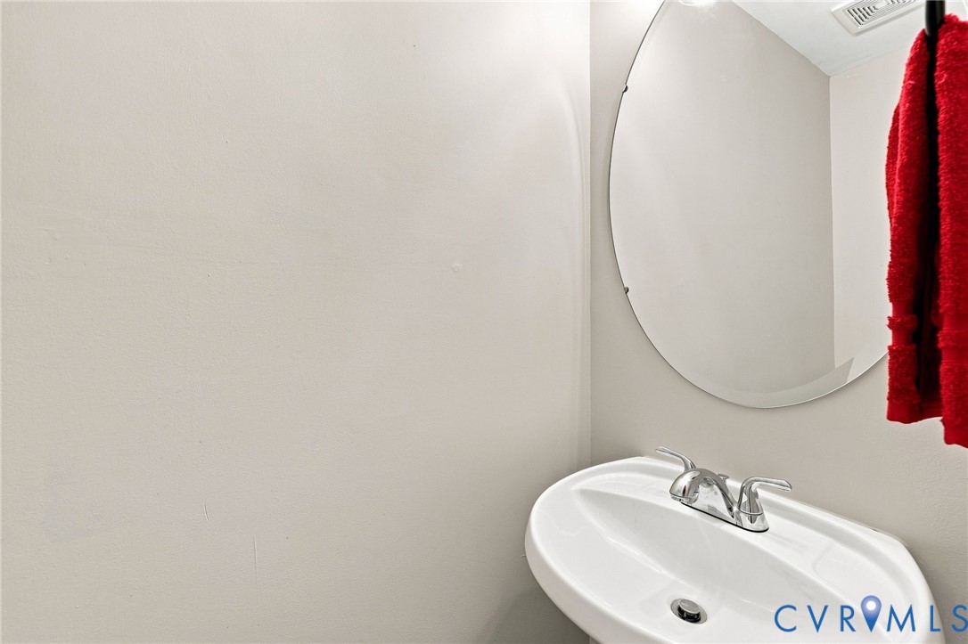 Pedestal sink with chrome-finish faucet and an oval wall mirror