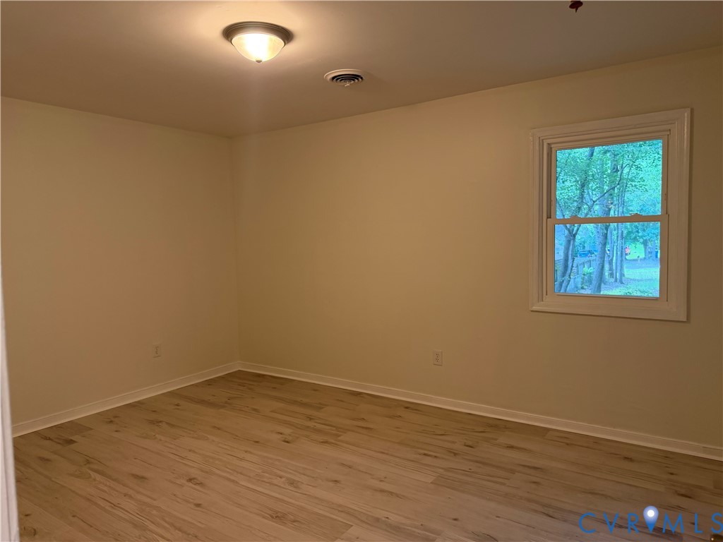 Neutral wall color, wood-finish flooring, single window, flush-mount ceiling light