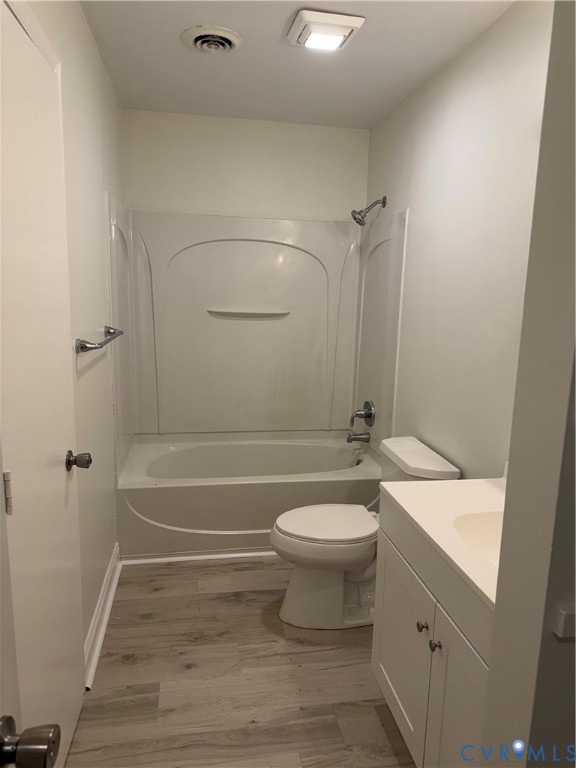 White-paneled bathtub and shower combination, with a white toilet, and a white vanity with an integrated sink