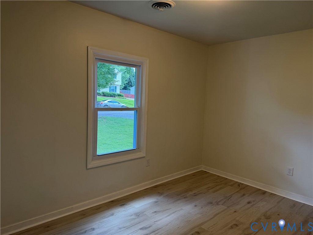 Hardwood-finish flooring, single window with white trim, light-colored walls, and a ceiling light fixture