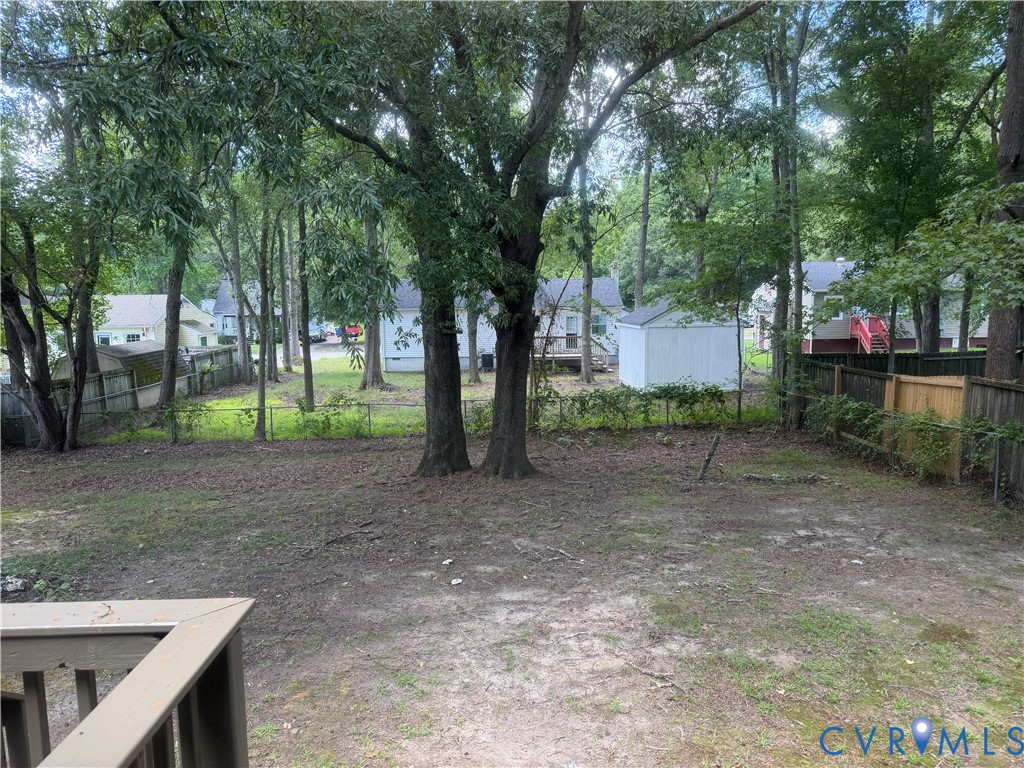 Expansive backyard featuring mature trees, a privacy fence, and a dedicated storage shed