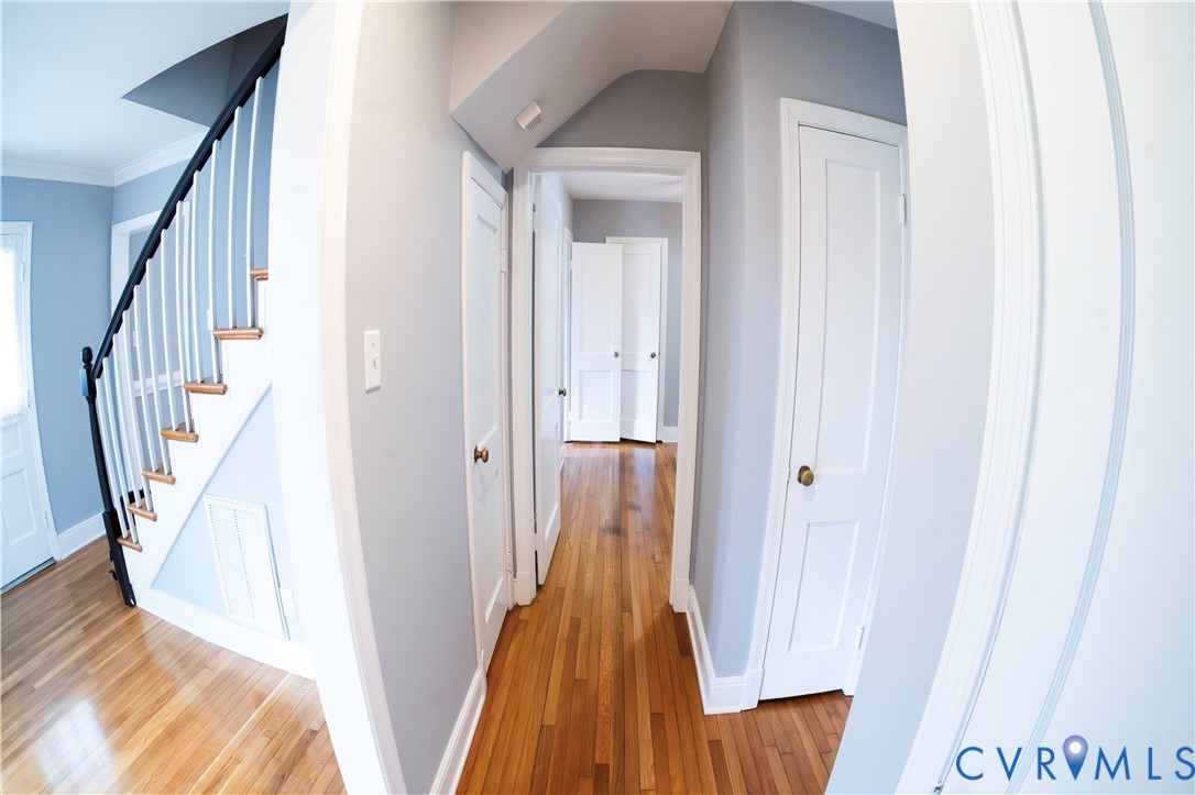 Hardwood flooring, painted walls, white trim, white doors, and a staircase with white risers and balusters