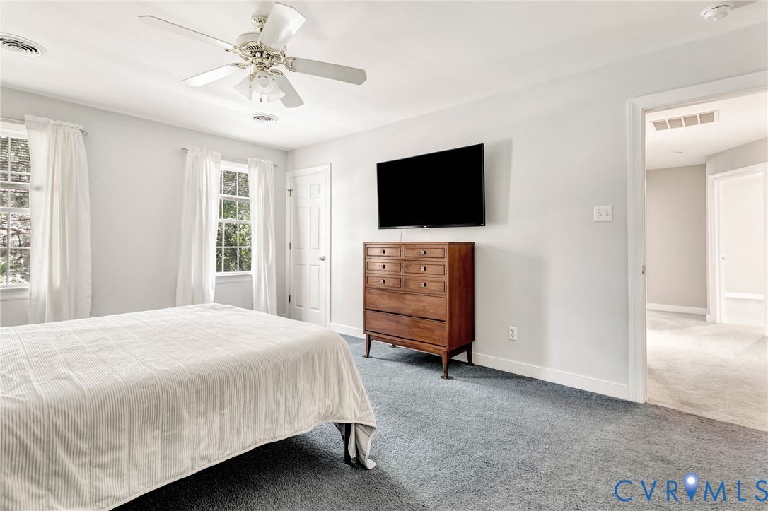 Light gray walls, light gray carpeting, two windows, and a ceiling fan with integrated lighting