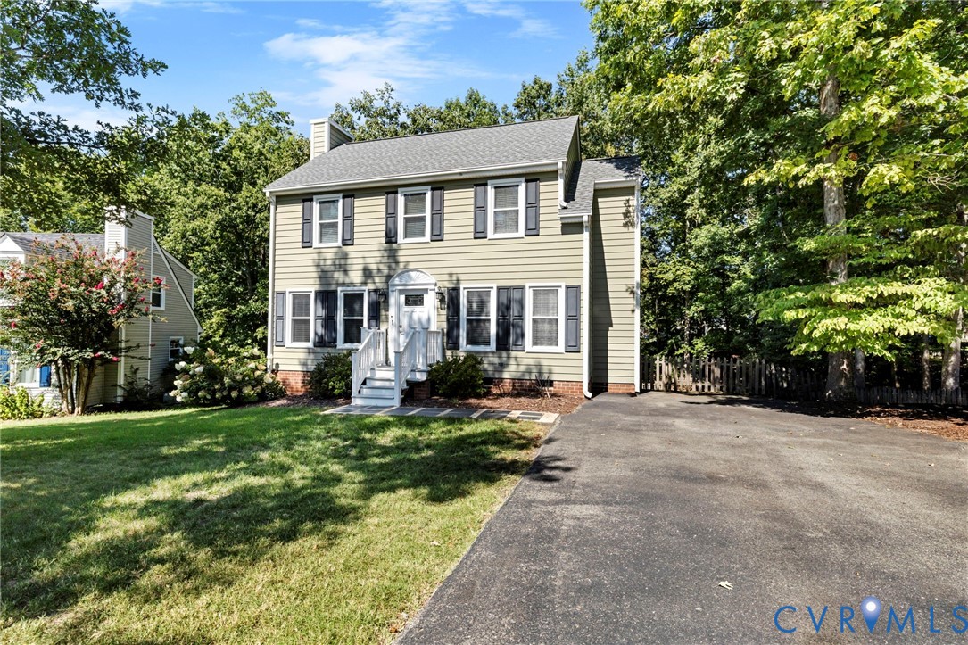 Two-story colonial-style residence featuring a prominent front porch, a well-maintained lawn, and mature trees providing natural shading Two-story colonial-style residence featuring a prominent front porch, a well-maintained lawn, and mature trees providing natural shading