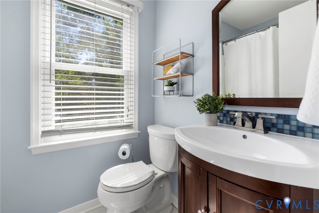 Curved-front vanity with a basin sink, wood-finish framed mirror, and mosaic tile backsplash