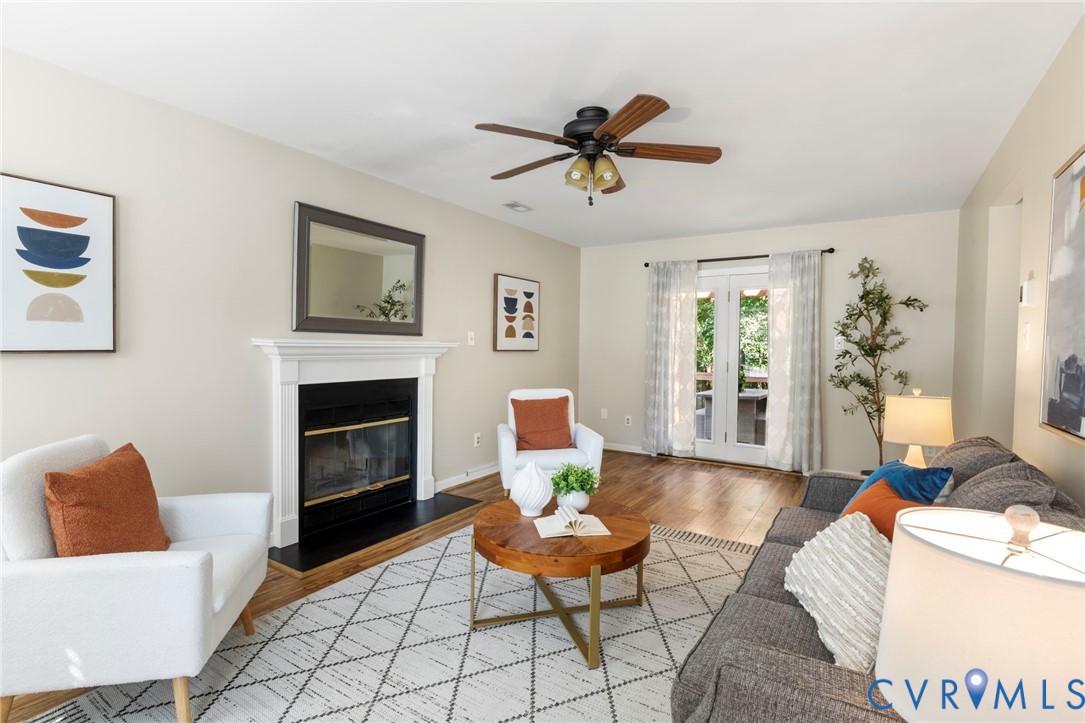 Living area featuring a fireplace with a white mantel, wood-finish flooring, and French doors Living area featuring a fireplace with a white mantel, wood-finish flooring, and French doors
