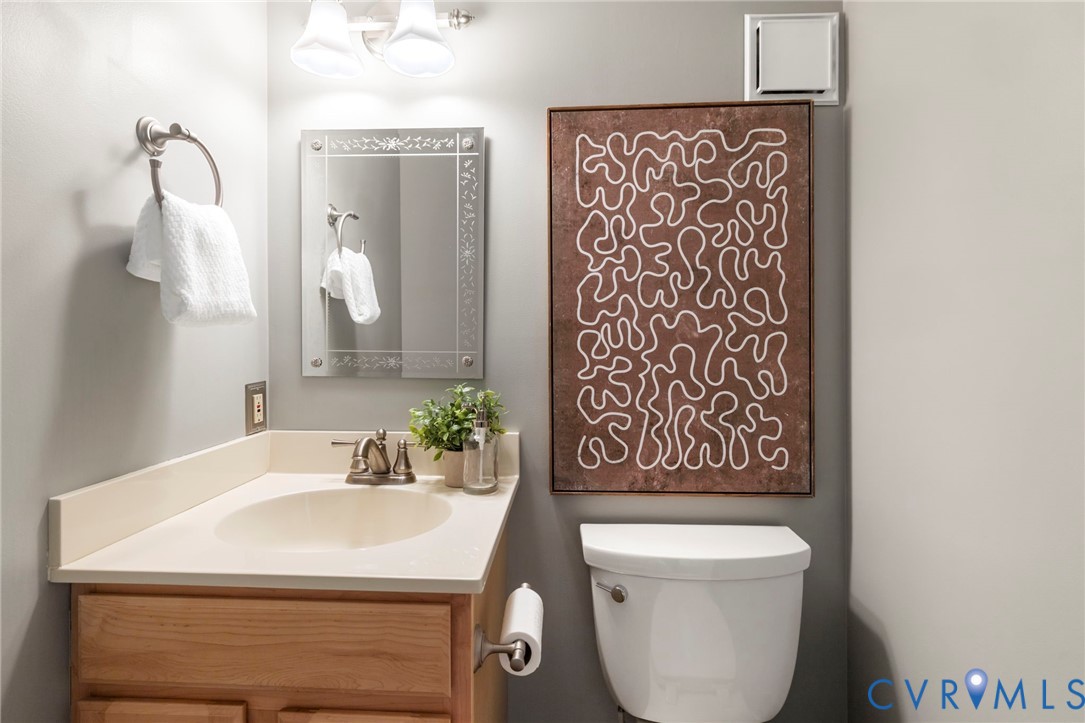 Light wood-finish vanity with a built-in sink, brushed nickel faucet, and coordinating towel ring