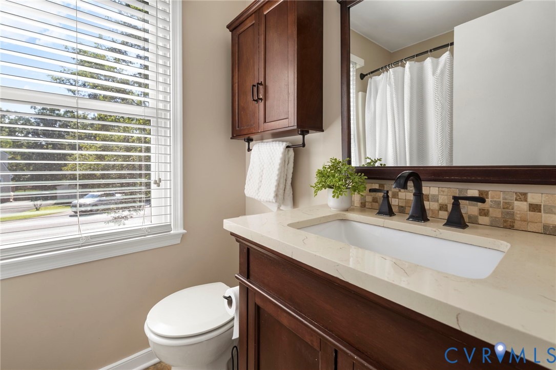 Wood-finish vanity with an integrated rectangular sink, light-toned countertop, and matte black faucet