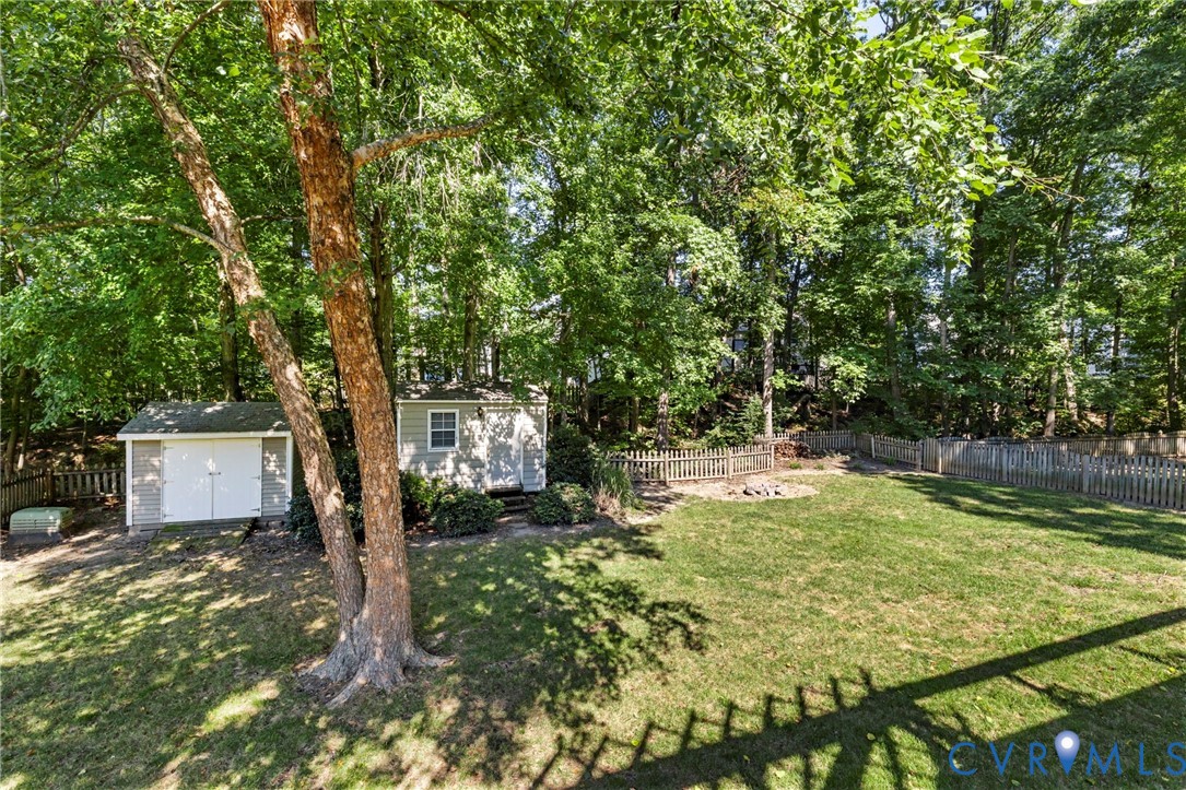 Expansive backyard featuring a manicured lawn, two detached storage sheds, and a perimeter fence