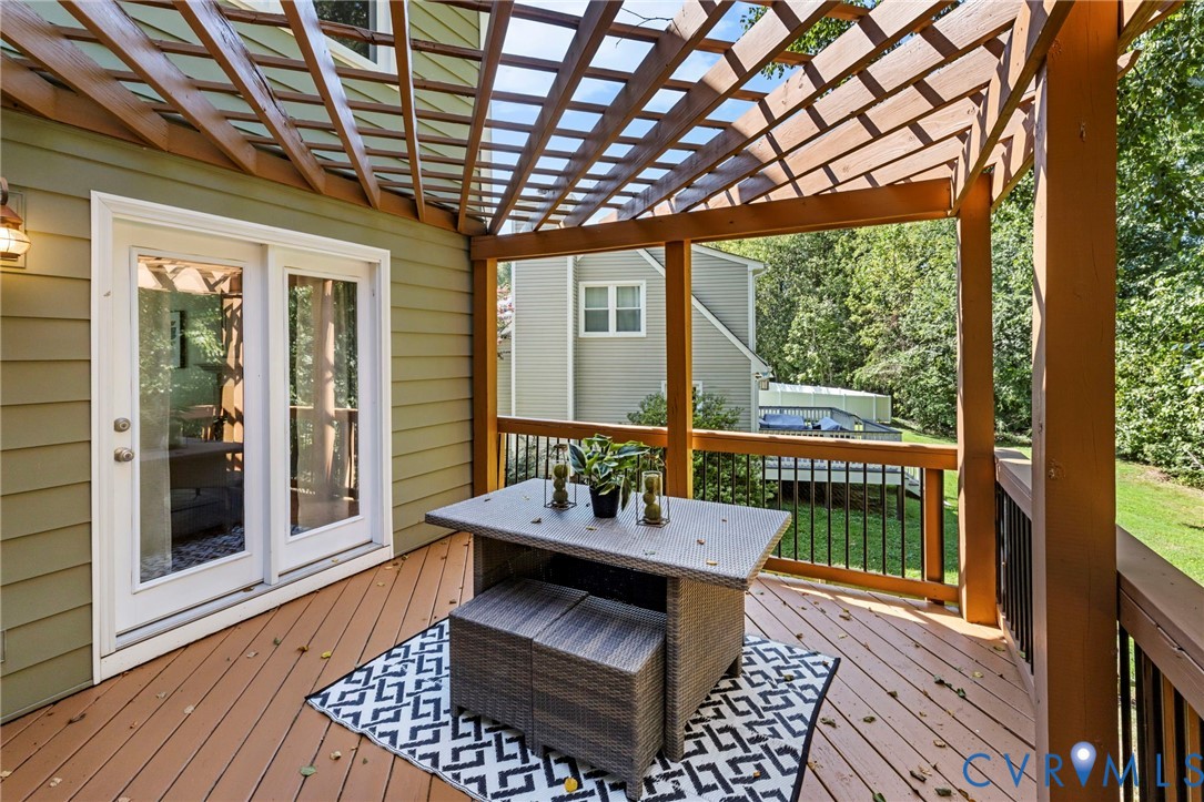Expansive outdoor deck featuring wood-finish flooring, a decorative wood pergola, and metal railings