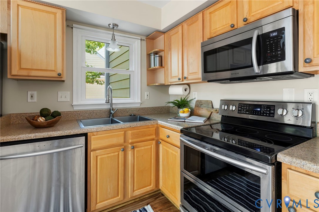 Kitchen featuring stainless steel appliances, light wood cabinetry, a double basin sink, and laminate countertops