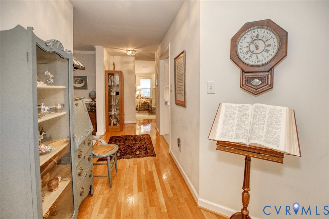 Charming hallway showcasing warm wood-finish flooring, white painted walls, and built-in cabinetry with glass-front doors