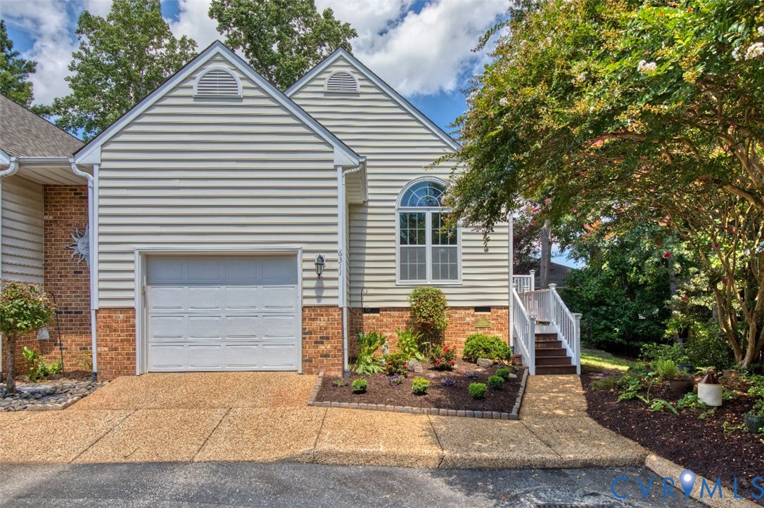 Charming residence showcasing a brick and horizontal siding exterior with a two-car garage featuring a white panel door Charming residence showcasing a brick and horizontal siding exterior with a two-car garage featuring a white panel door