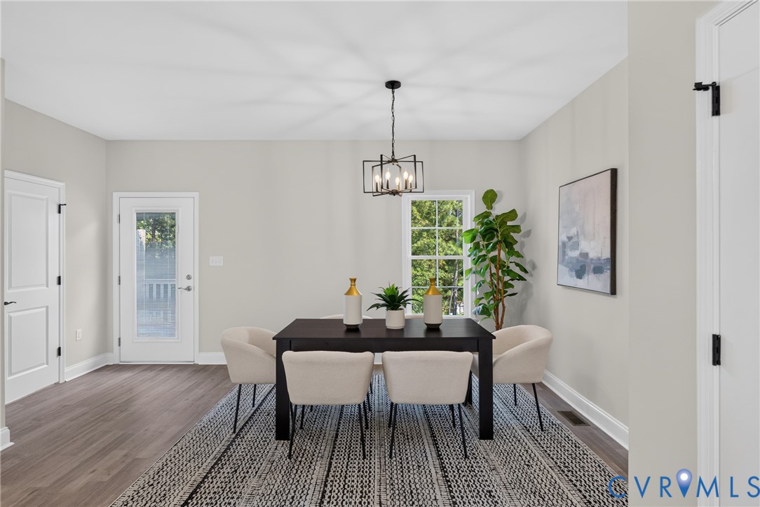 Light gray wall finishes, wood-finish flooring, a contemporary chandelier, white trim, and a glass-paneled door