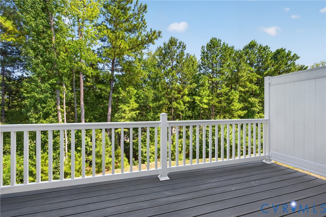 Deck featuring composite planking, white railing, and a privacy wall