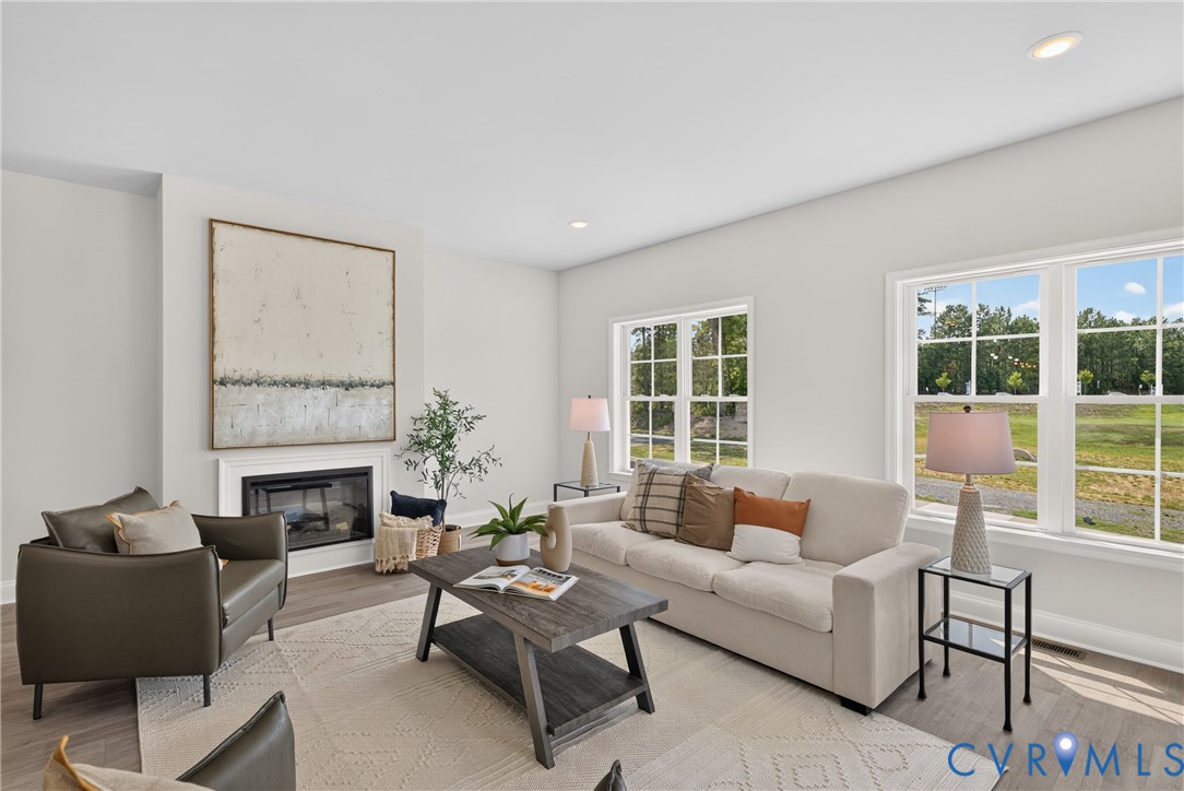 Recessed lighting, wood-finish flooring, white walls, and a built-in fireplace with a white mantel and surround