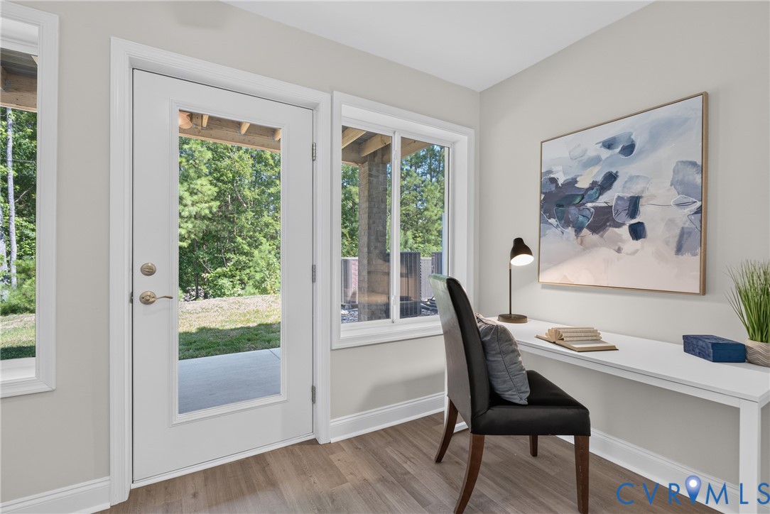 Wood-finish flooring, white trim, and a full-light exterior door