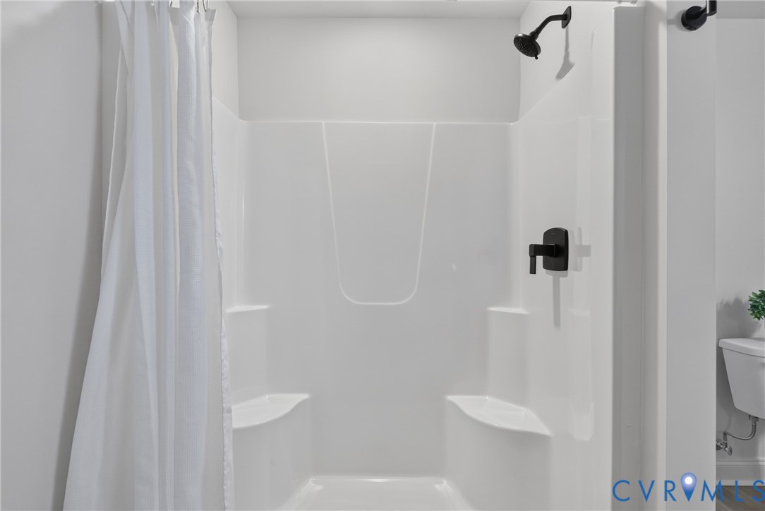 Shower featuring matte black fixtures and built-in shelving
