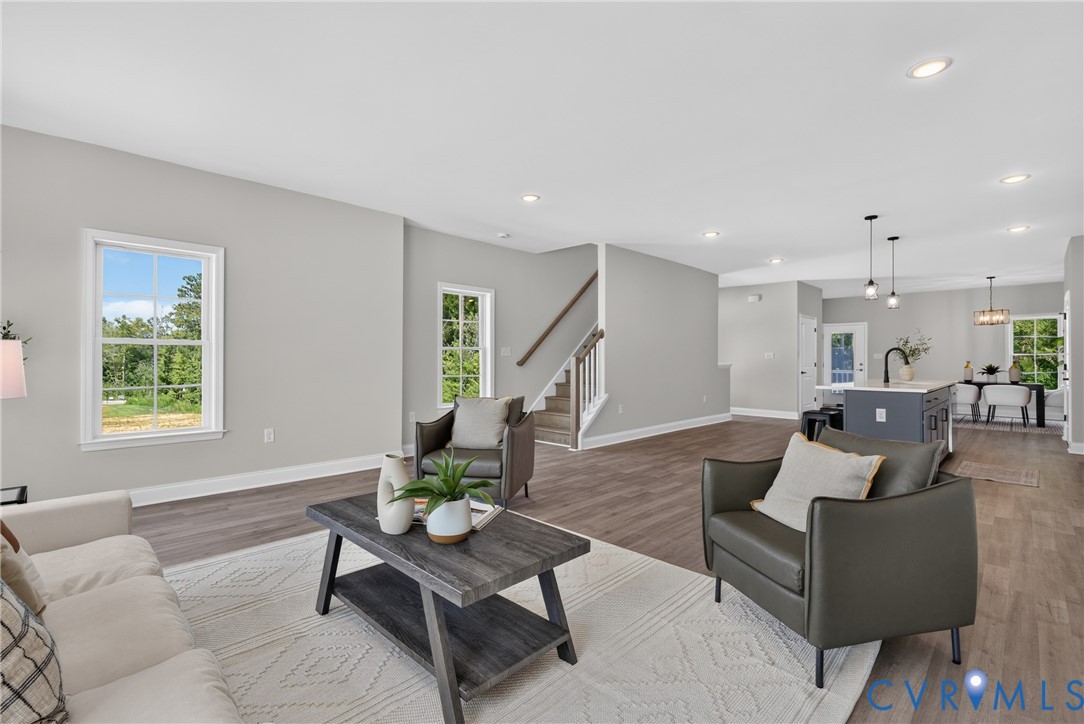 Open-concept living area with wood-finish flooring, recessed lighting, and multiple windows