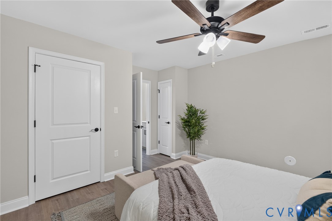 Wood-finish flooring, white panel doors with matte black hardware, and a ceiling fan with integrated lighting