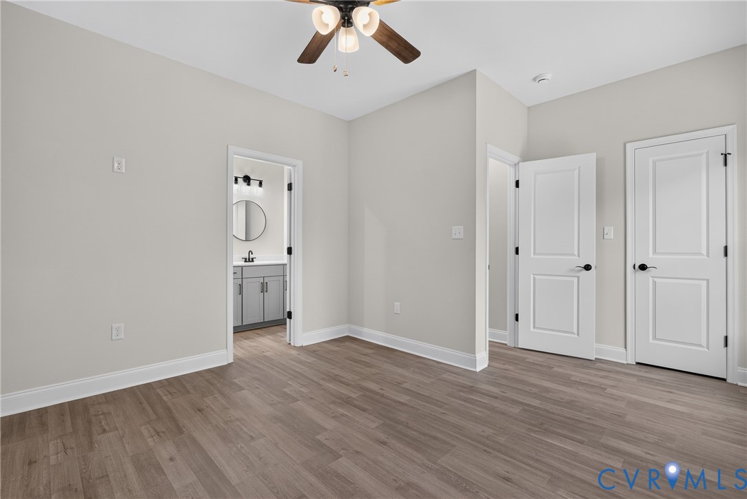Wood-finish flooring, white paneled doors with matte black hardware, and a ceiling fan with light fixture