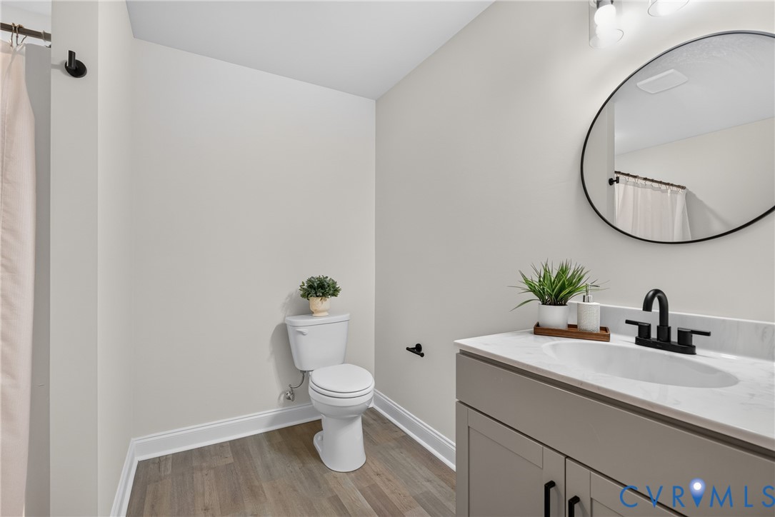 Wood-finish flooring, white walls, and a white toilet