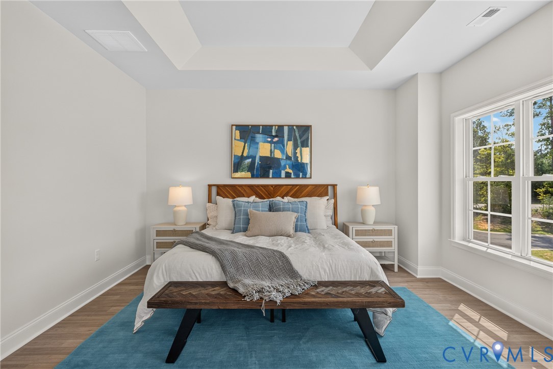 Tray ceiling with recessed lighting, wood-finish flooring, and white trim