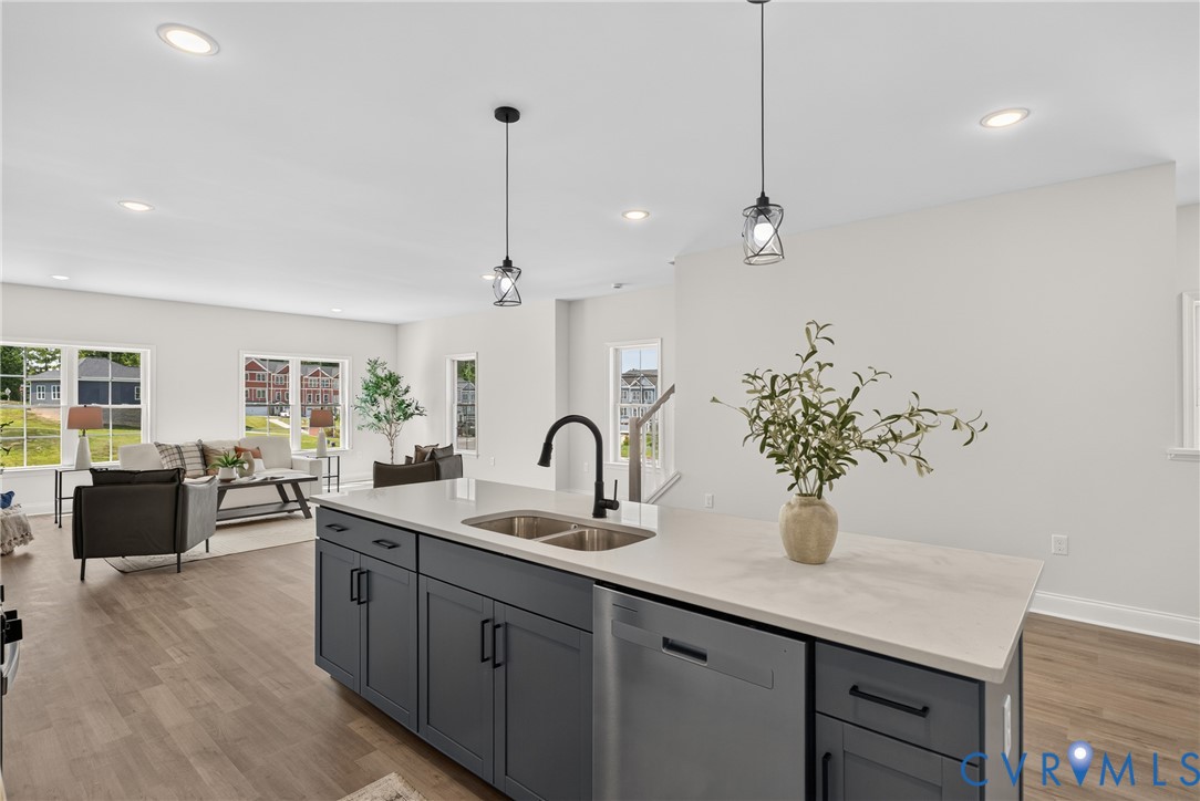 Kitchen island featuring dark cabinetry, stainless steel dishwasher, and dual basin sink with a matte black faucet