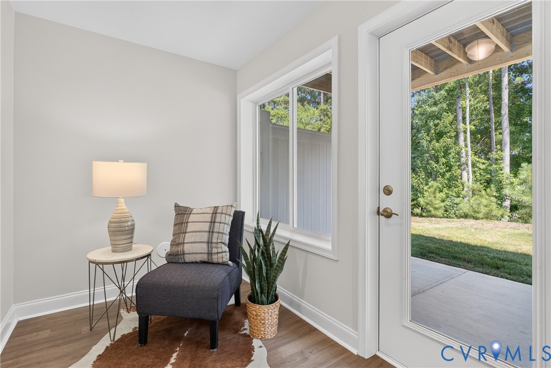 Light gray wall paint, wood-finish flooring, white trim, sliding window, and a full-light glass door leading to an outdoor patio