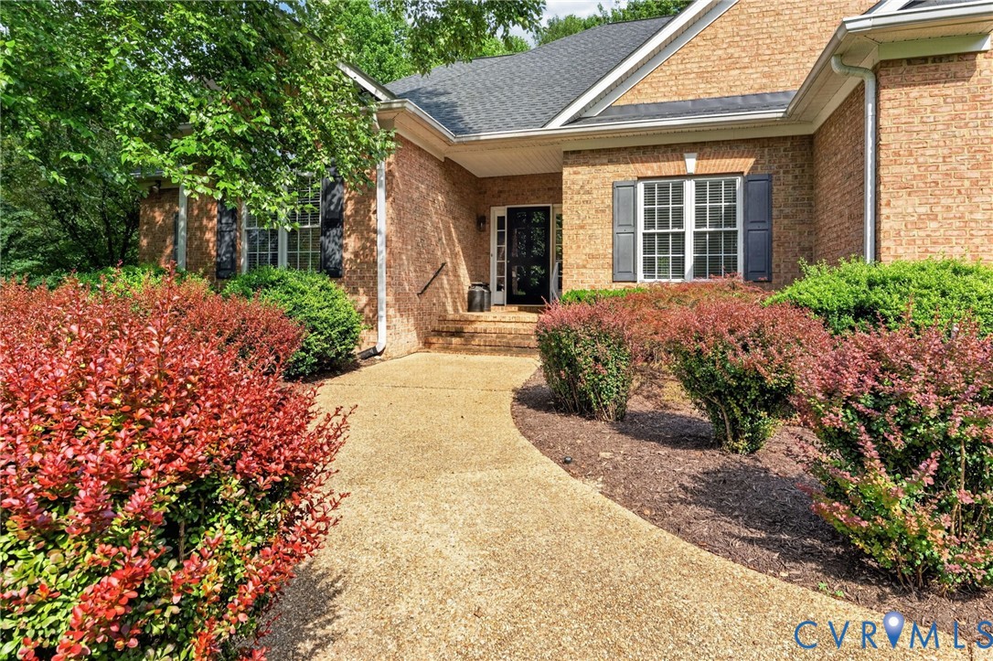 Brick exterior with a gabled roofline, complemented by a concrete aggregate pathway Brick exterior with a gabled roofline, complemented by a concrete aggregate pathway