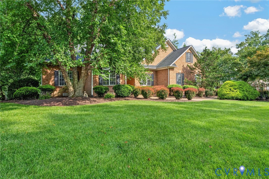 Brick Colonial residence showcasing a manicured front lawn, mature landscaping with established trees, and professionally maintained foundation plantings Brick Colonial residence showcasing a manicured front lawn, mature landscaping with established trees, and professionally maintained foundation plantings