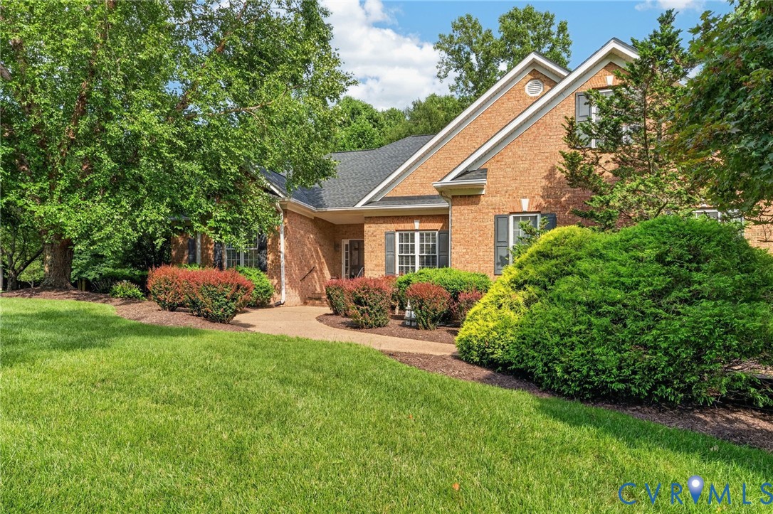 Brick exterior with gabled roofline, featuring a concrete pathway, manicured lawn, and mature trees Brick exterior with gabled roofline, featuring a concrete pathway, manicured lawn, and mature trees