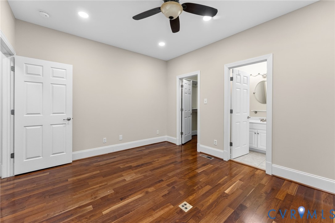 Hardwood flooring, recessed lighting, ceiling fan, white paneled doors, and a vanity with a round mirror