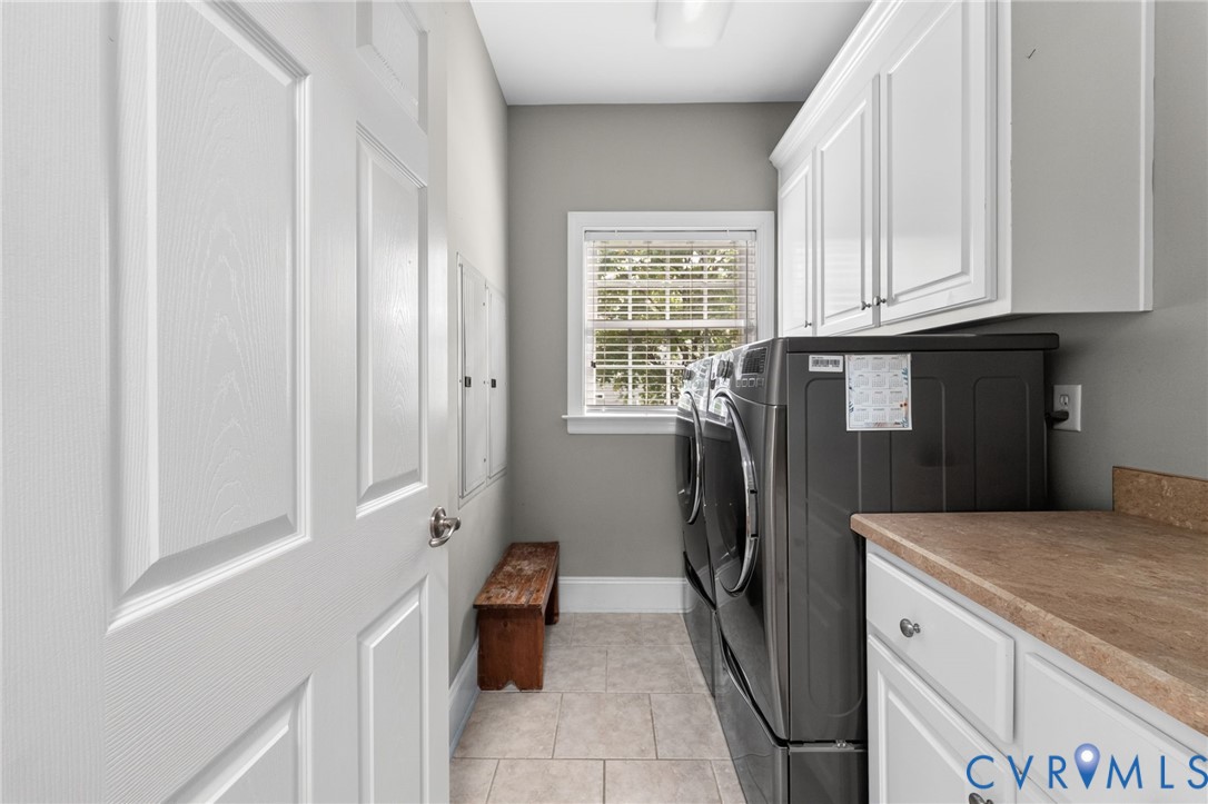Laundry room featuring tiled flooring, built-in cabinetry, a window with blinds, and a countertop