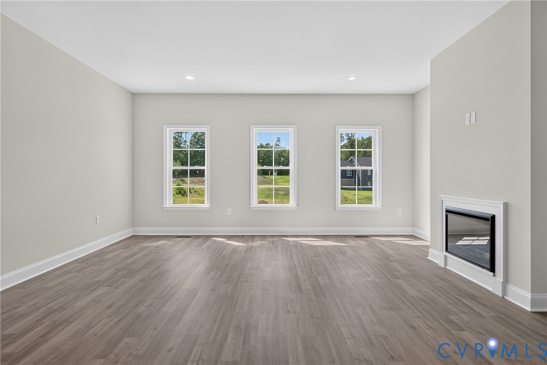 Spacious room featuring wood-finish flooring, recessed lighting, and three bright windows