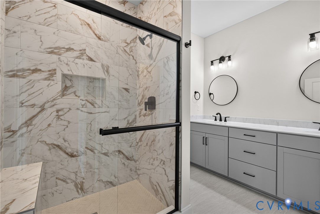 Walk-in shower with natural stone-look tile, built-in niche, and bench seating