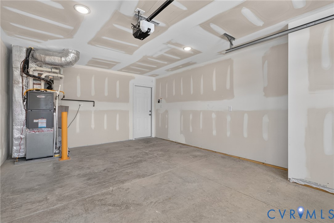 Concrete flooring, recessed lighting, white door, exposed HVAC system, garage door opener