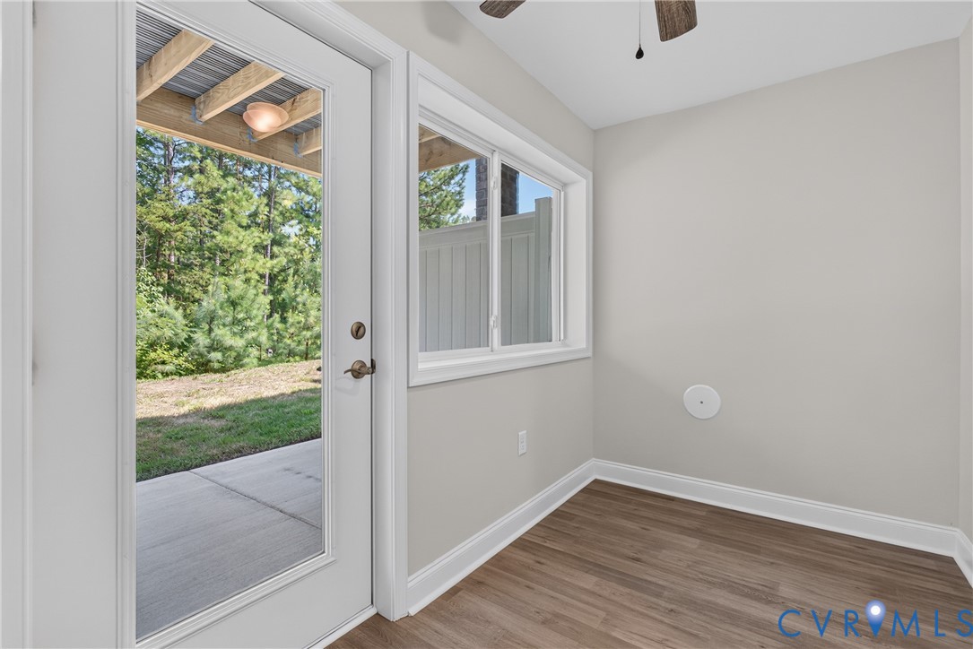Full-light exterior door with clear glass, wood-finish flooring, and a ceiling fan Full-light exterior door with clear glass, wood-finish flooring, and a ceiling fan