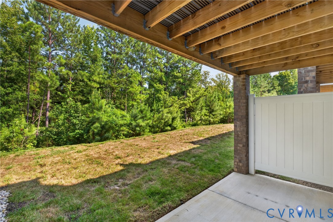 Covered outdoor patio with a concrete surface, wooden joist ceiling, and a privacy fence
