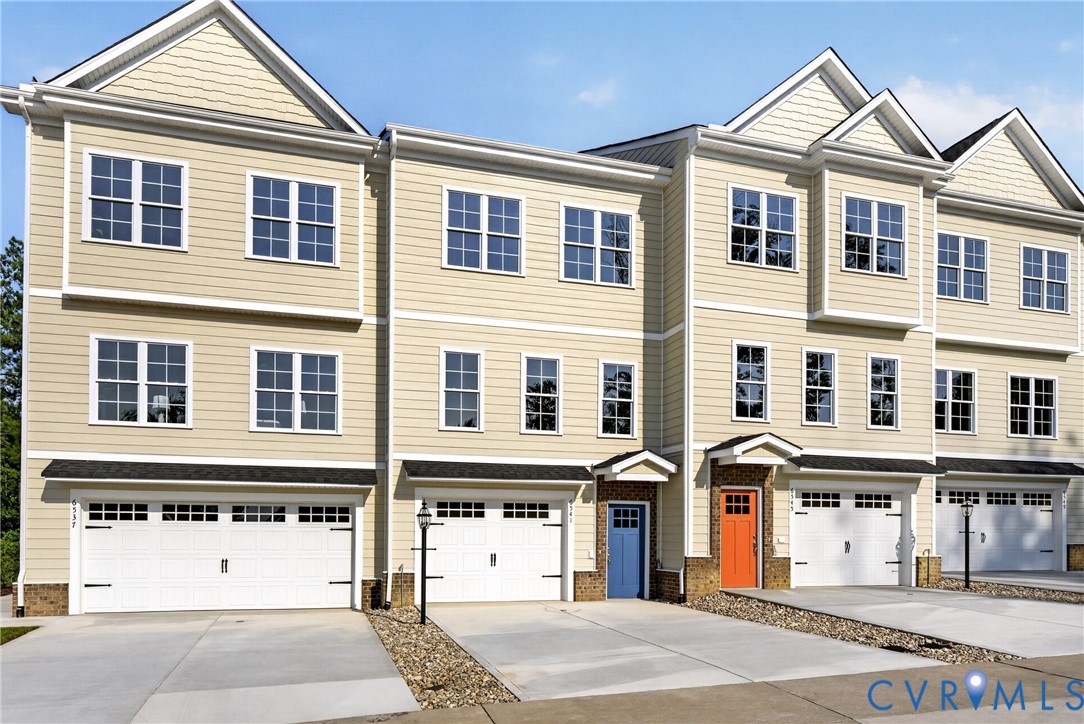 Three-story townhome with light-toned siding and multiple windows