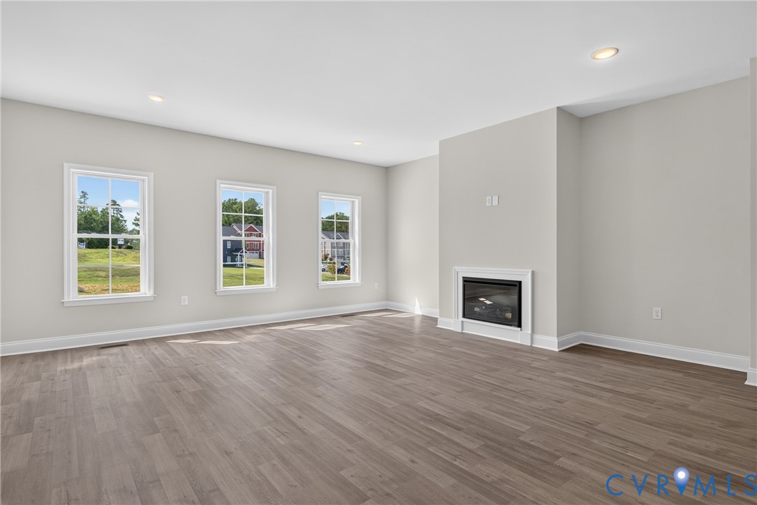 Wood-finish flooring, recessed lighting, and a built-in fireplace with a white mantel