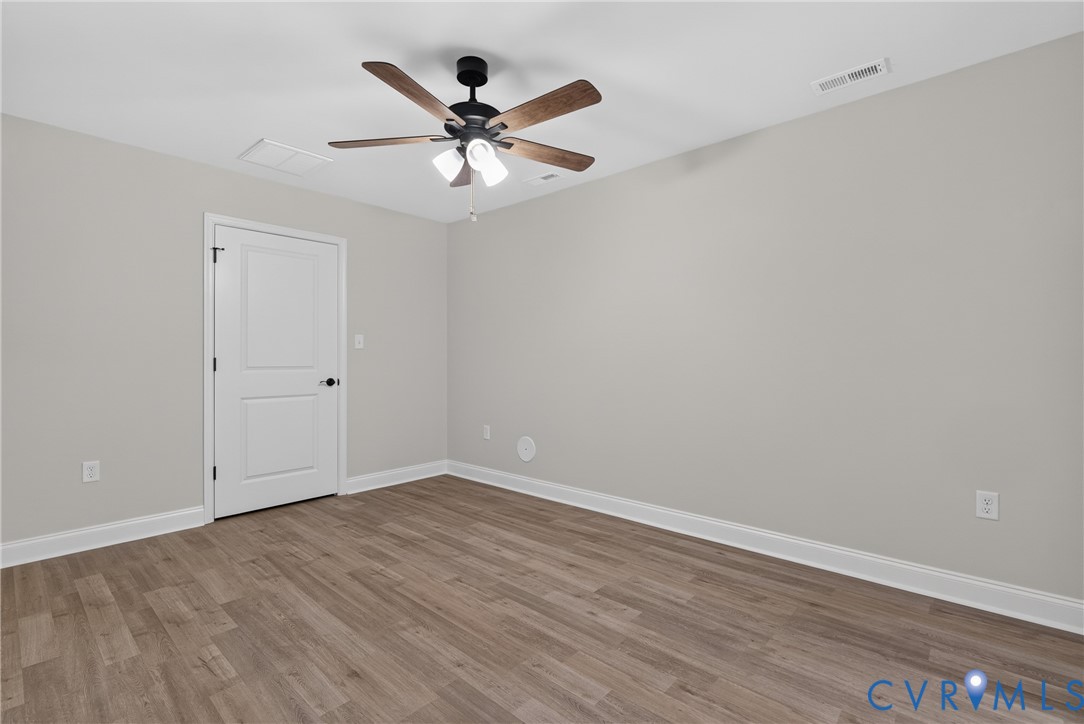 Wood-finish flooring, light gray wall paint, and a ceiling fan with integrated lighting Wood-finish flooring, light gray wall paint, and a ceiling fan with integrated lighting