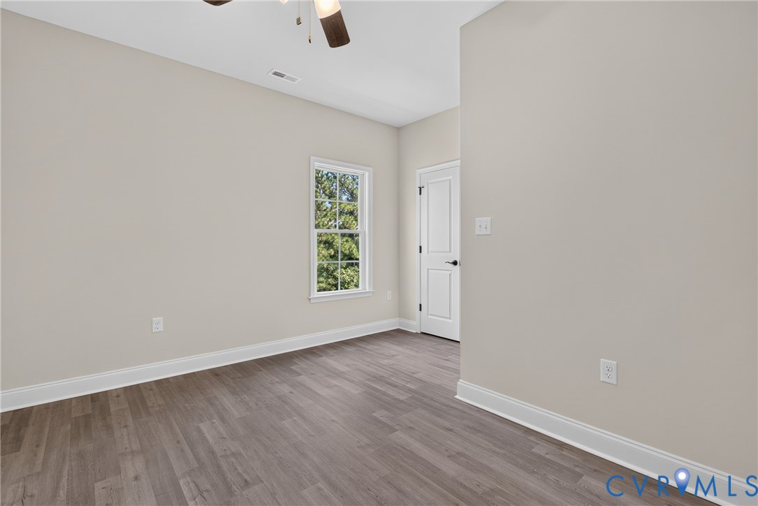 Wood-finish flooring, white trim, single window, white interior door, and ceiling fan