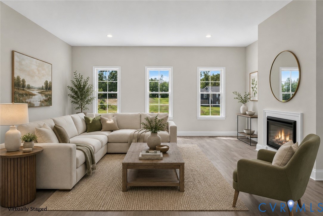 Spacious room featuring multiple windows, wood-finish flooring, recessed lighting, and a built-in fireplace with a classic mantel