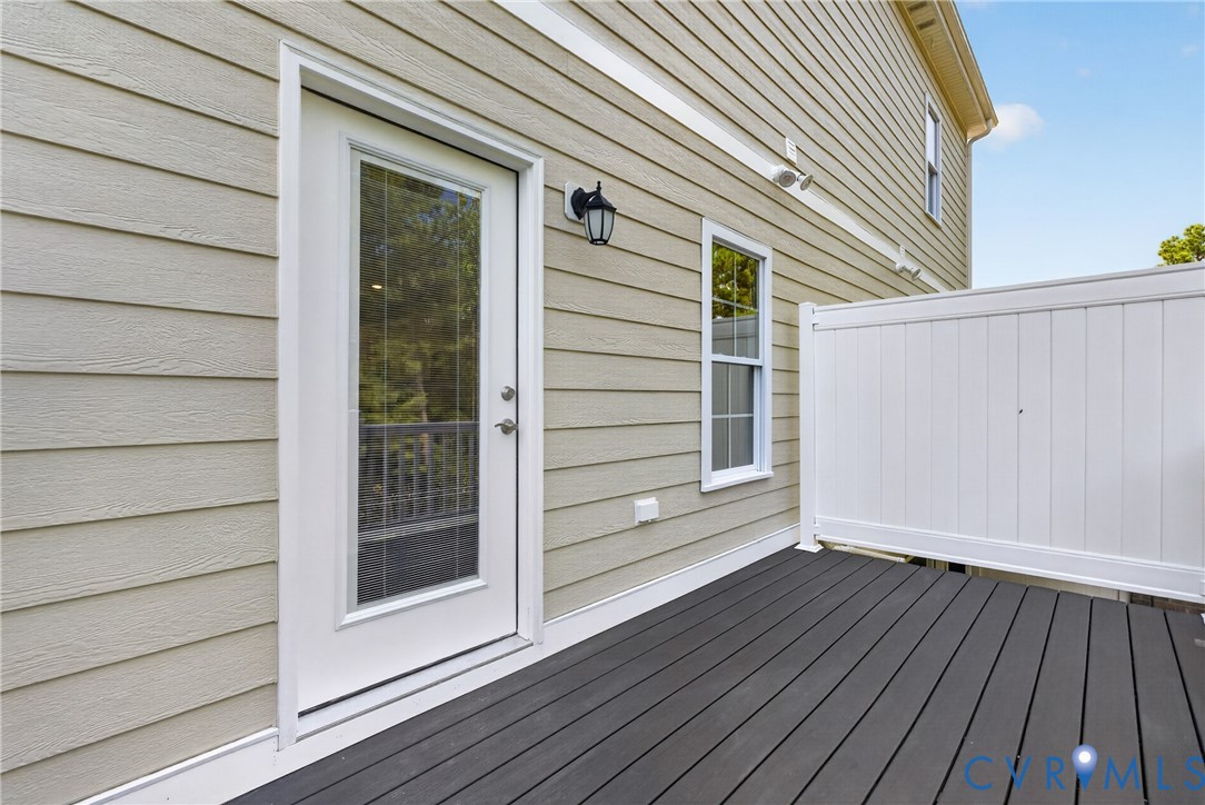 Exterior deck featuring composite decking, white privacy fencing, and a full-light door